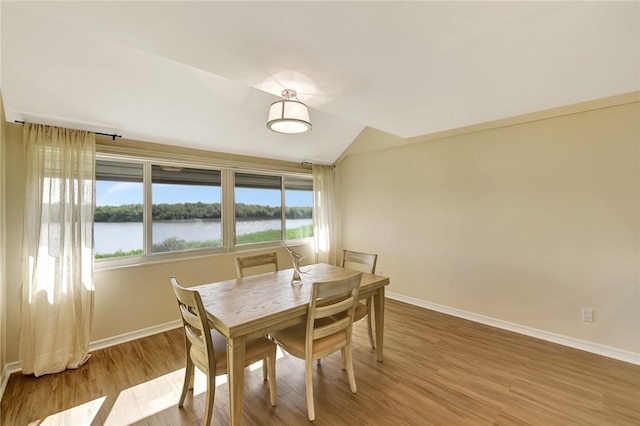 dining room featuring a water view, lofted ceiling, and hardwood / wood-style floors