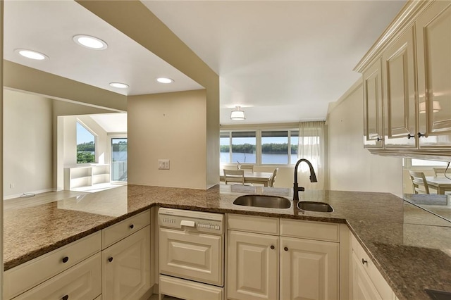 kitchen with a wealth of natural light, dishwasher, sink, kitchen peninsula, and a water view