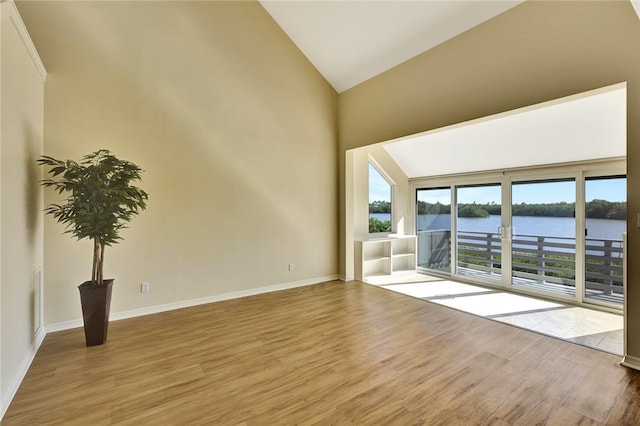 spare room featuring vaulted ceiling, a water view, and light wood-type flooring