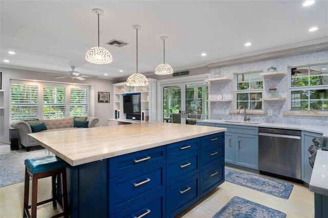 kitchen featuring stainless steel dishwasher, open floor plan, blue cabinets, open shelves, and light countertops