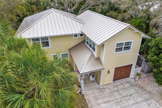 view of front of property with an attached garage, driveway, and metal roof