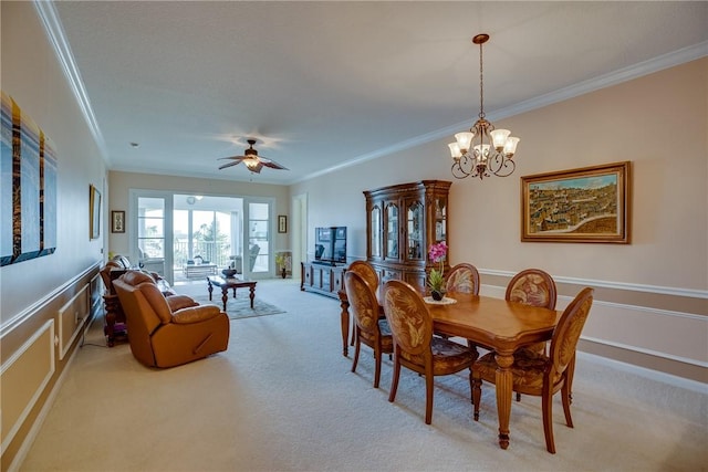 carpeted dining space with ceiling fan with notable chandelier and crown molding