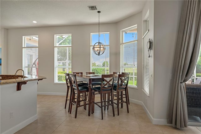 tiled dining area featuring an inviting chandelier, sink, and a textured ceiling