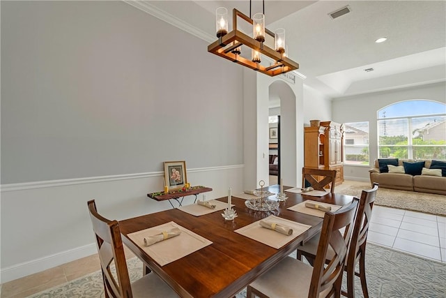 tiled dining space with a notable chandelier, crown molding, and a raised ceiling