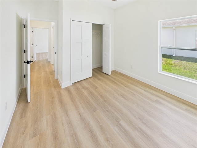 unfurnished bedroom with a closet, light wood-style flooring, and baseboards