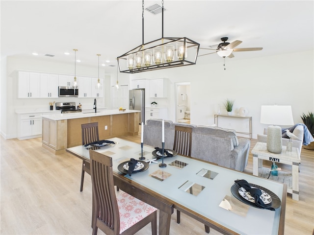 dining space featuring light wood-style floors, ceiling fan with notable chandelier, visible vents, and recessed lighting