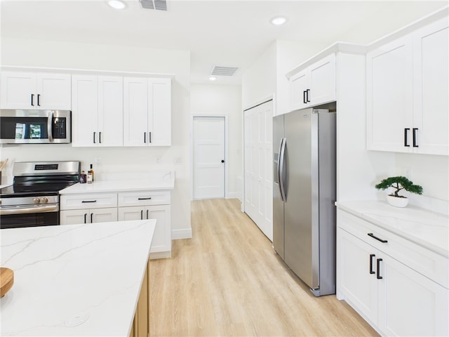 kitchen with light wood-style flooring, white cabinetry, and stainless steel appliances
