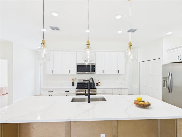 kitchen with a sink, visible vents, appliances with stainless steel finishes, and a kitchen island with sink