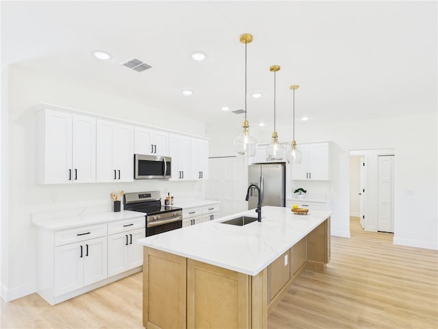 kitchen with visible vents, a large island, appliances with stainless steel finishes, a sink, and light wood finished floors