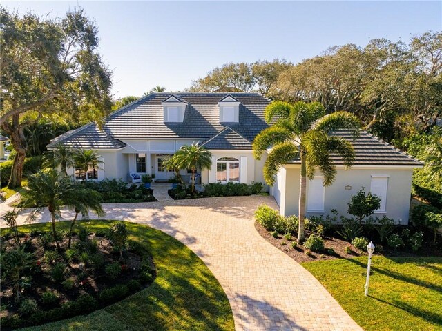 351 Marbrisa Dr, Vero Beach, FL 32963 - view of front facade with curved driveway, stucco siding, a front lawn, and a tiled roof