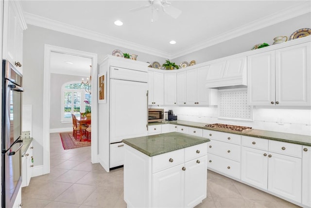 kitchen with light tile patterned floors, premium range hood, appliances with stainless steel finishes, decorative backsplash, and crown molding