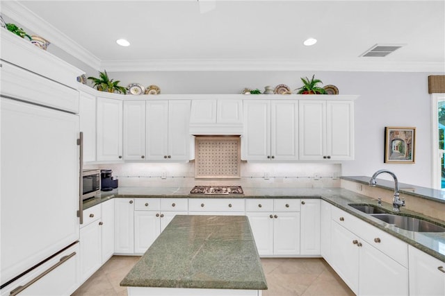 kitchen featuring sink, white cabinetry, a center island, dark stone counters, and stainless steel appliances