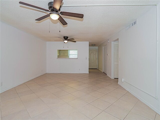 tiled empty room with ceiling fan and a textured ceiling