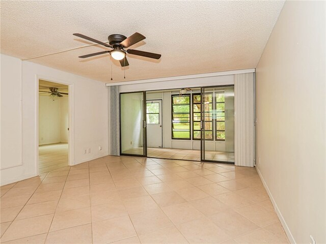 unfurnished room with a textured ceiling, ceiling fan, and light tile patterned flooring