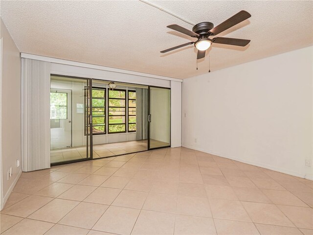 empty room featuring ceiling fan, a textured ceiling, and light tile patterned floors