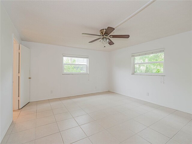 spare room featuring a wealth of natural light, a textured ceiling, light tile patterned floors, and ceiling fan