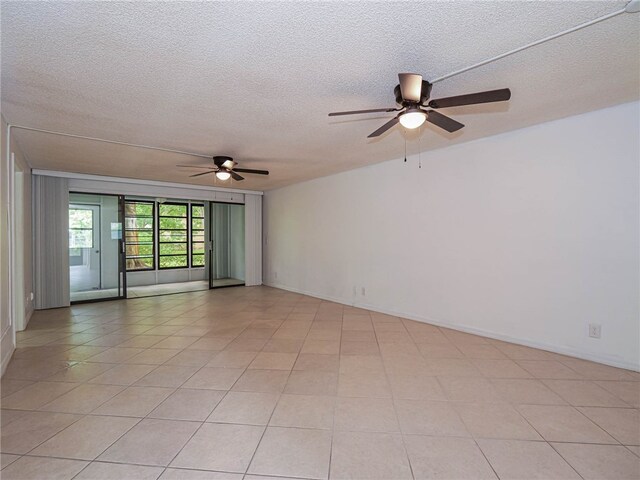 tiled empty room featuring ceiling fan and a textured ceiling