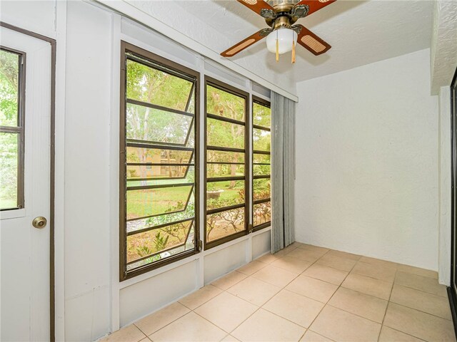 unfurnished room featuring a wealth of natural light, light tile patterned floors, and ceiling fan