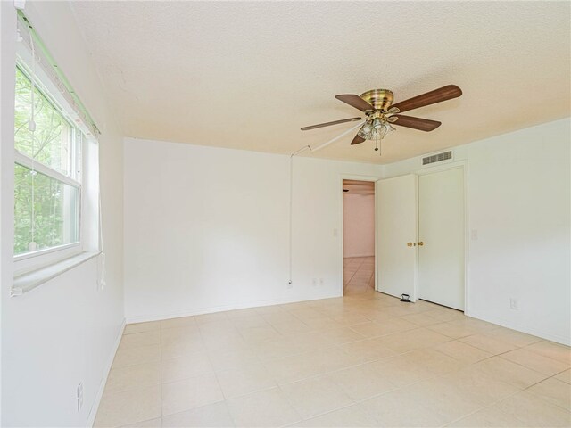 unfurnished room with ceiling fan, a textured ceiling, and light tile patterned floors