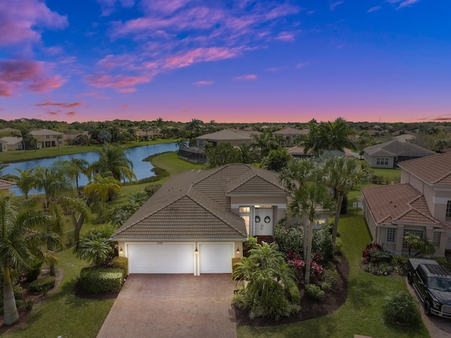 view of front of property featuring a garage, a water view, and a lawn