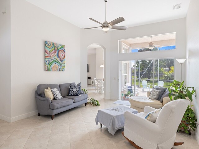 tiled living room featuring ceiling fan and a high ceiling