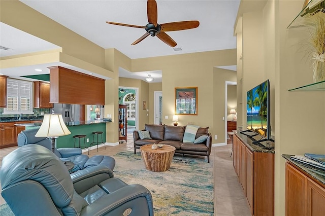 living area with light tile patterned floors, ceiling fan, visible vents, and baseboards