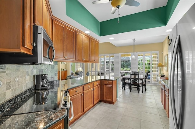 kitchen featuring tasteful backsplash, ceiling fan, stainless steel appliances, a peninsula, and brown cabinetry