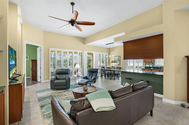 living area featuring baseboards, light tile patterned floors, and a ceiling fan
