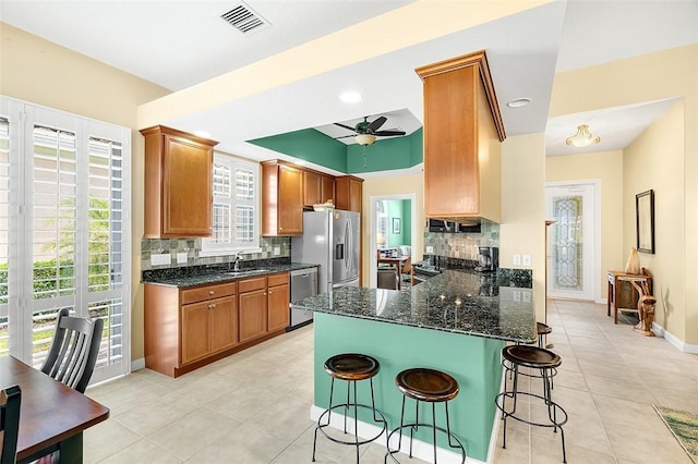 kitchen with a sink, ceiling fan, tasteful backsplash, visible vents, and appliances with stainless steel finishes