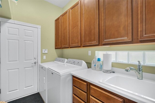 washroom featuring independent washer and dryer, cabinet space, and a sink