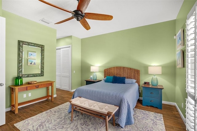 bedroom featuring visible vents, baseboards, a closet, wood finished floors, and a ceiling fan