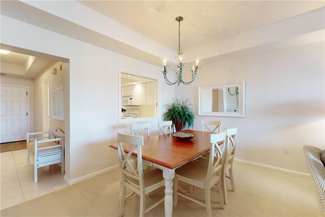 dining area with a tray ceiling, light colored carpet, and a notable chandelier