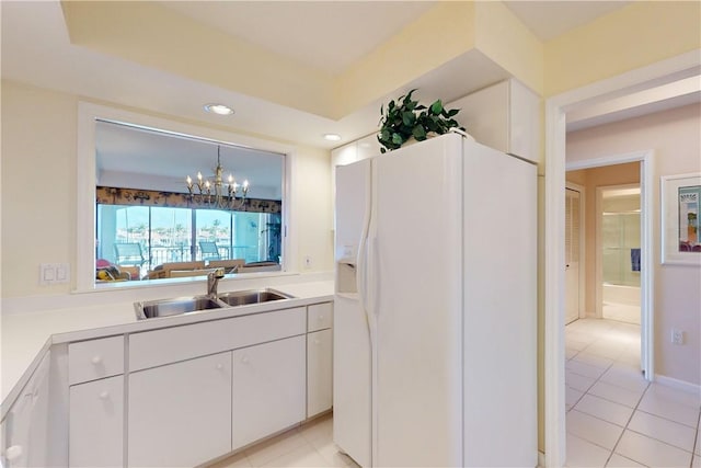 kitchen featuring white cabinets, sink, hanging light fixtures, white fridge with ice dispenser, and a chandelier