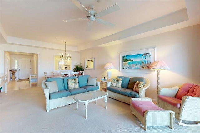 carpeted living room with a tray ceiling and ceiling fan with notable chandelier