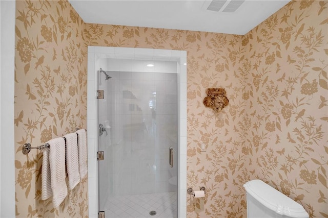 bathroom with toilet, a shower stall, and wallpapered walls