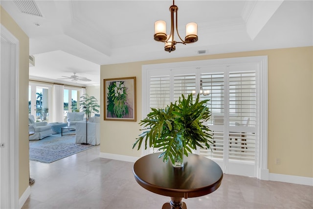 foyer entrance with a raised ceiling, crown molding, baseboards, and visible vents