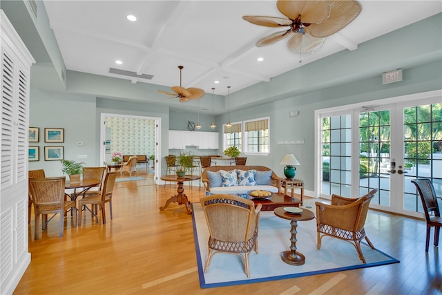 living area featuring a ceiling fan, light wood finished floors, coffered ceiling, french doors, and beamed ceiling