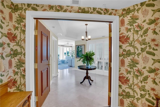 hall featuring wallpapered walls, an inviting chandelier, and visible vents