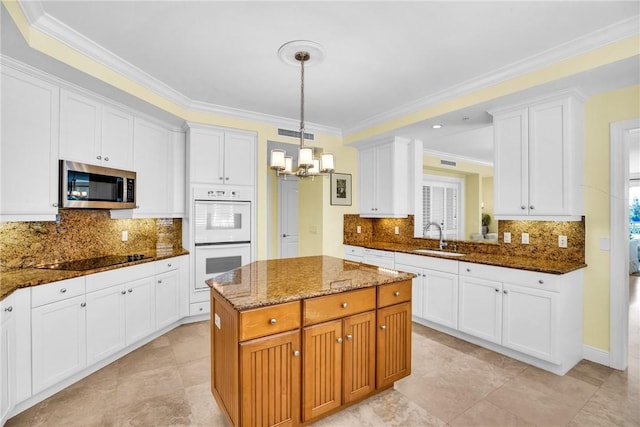 kitchen with stainless steel microwave, white double oven, black electric stovetop, dark stone countertops, and an inviting chandelier