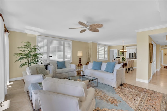 living room featuring ceiling fan with notable chandelier, baseboards, and ornamental molding