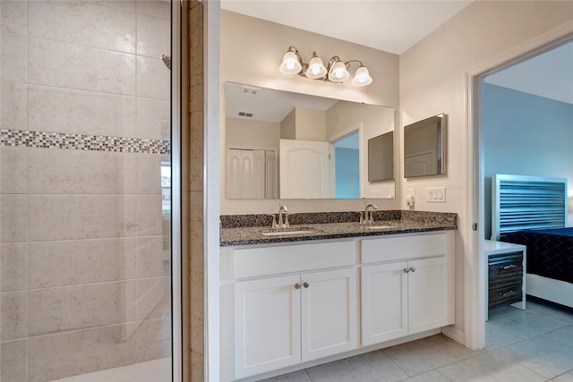 ensuite bathroom featuring double vanity, a stall shower, tile patterned flooring, and a sink