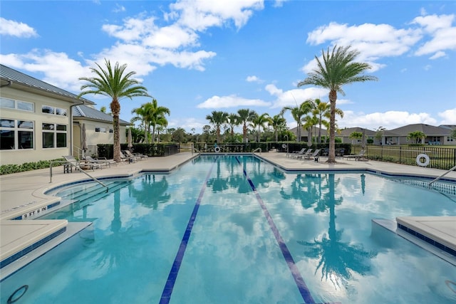 community pool with a patio area and fence