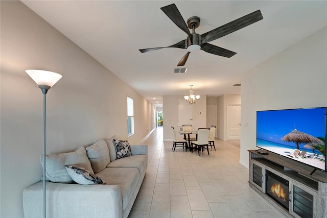 living area featuring ceiling fan with notable chandelier, light tile patterned floors, a glass covered fireplace, and visible vents