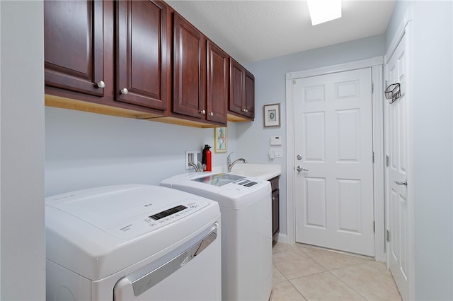 washroom with cabinets, a textured ceiling, light tile patterned floors, sink, and washer and dryer