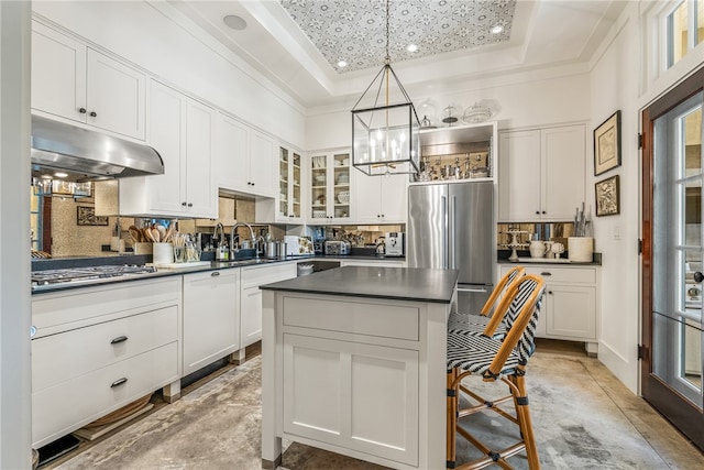 kitchen featuring stainless steel appliances, white cabinetry, hanging light fixtures, and a tray ceiling