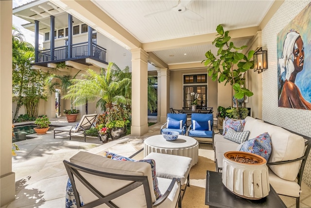 view of patio with an outdoor living space, ceiling fan, and a balcony