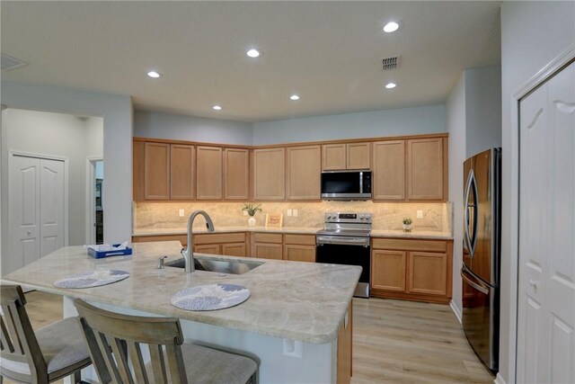 240 Barbossa Dr, Sebastian, FL 32958 - kitchen featuring stainless steel appliances, light wood-style flooring, tasteful backsplash, light stone counters, and a kitchen breakfast bar