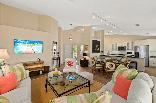 living room featuring sink, light tile patterned floors, track lighting, and high vaulted ceiling