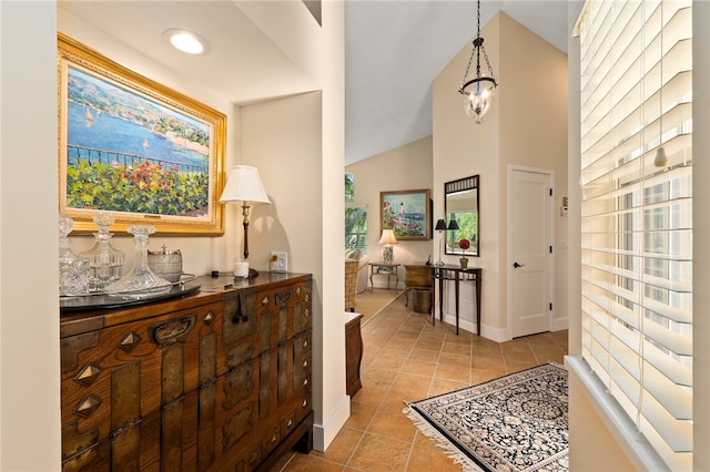 corridor with a chandelier, light tile patterned floors, and vaulted ceiling