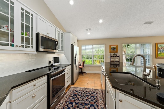 kitchen with backsplash, sink, light tile patterned floors, white cabinetry, and stainless steel appliances